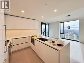 Burnaby apartment for rent - A modern kitchen with white cabinets and a large window overlooking the city.