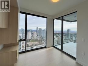 Burnaby apartment for rent - A spacious room with a view of the cityscape through large windows.