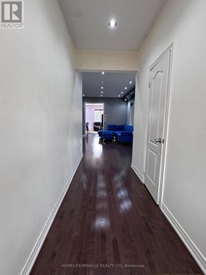 Brampton (Bram East) apartment for rent - A long hallway with a door on the right and a room with blue chairs in the distance.