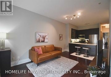 Markham (Unionville) condo for rent - A living room with a brown couch and a framed picture of a cow on the wall.