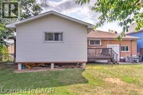 Brantford apartment for rent - A small house with a porch is surrounded by a grassy area.