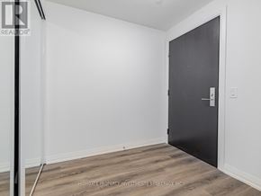 Vaughan (Vellore Village) condo for rent - A black door is on the right side of a room with white walls and wooden flooring.
