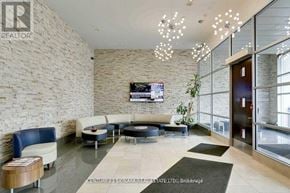Mississauga (City Centre) condo for rent - A reception area with a stone wall and a flat screen TV mounted on it.