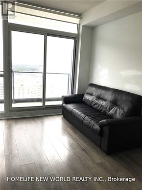 Toronto (Henry Farm) condo for rent - A black leather sofa sits in a bright room with a large window.