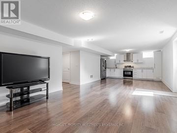 Pickering apartment for rent - A spacious living room with a television and a kitchen in the background.