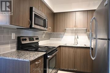 Toronto (Dovercourt-Wallace Emerson-Junction) condo for rent - A kitchen with wooden cabinets and a stainless steel refrigerator.
