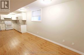 Barrie (Cundles East) apartment for rent - A room with wooden floors and white walls, with a window and a kitchen area in the background.
