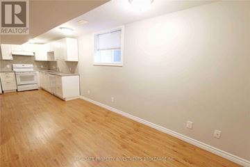 Barrie (Cundles East) apartment for rent - A room with wooden floors and white walls, with a window and a kitchen area in the background.
