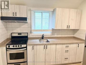 Niagara Falls (Downtown) multi-family for rent - A kitchen with white cabinets and a black stove top oven.