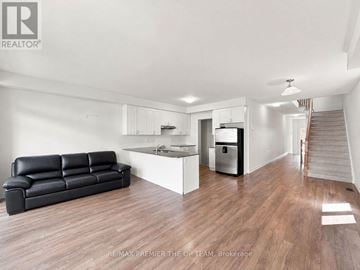 Erin apartment for rent - A black leather sofa sits in a spacious living room with hardwood floors and white walls.