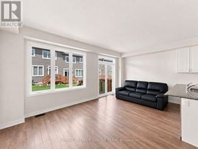 Erin apartment for rent - A living room with a black leather couch and a large window showing a view of a house.