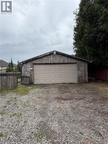 Hamilton apartment for rent - A wooden garage with a white door is situated in a gravel driveway.