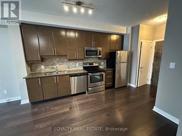 Toronto (Waterfront Communities) condo for rent - A kitchen with wooden cabinets and stainless steel appliances.