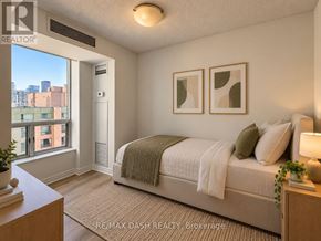 Toronto (Moss Park) condo for rent - A bedroom with a bed, nightstand, and window overlooking a cityscape.