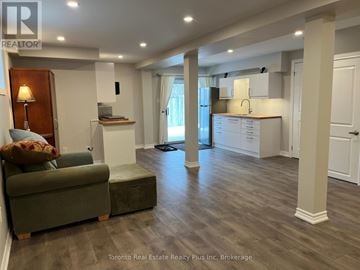 Barrie (Ardagh) apartment for rent - A well-lit, spacious living room with a green couch and a wooden floor.
