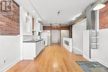 Toronto (South Riverdale) apartment for rent - A kitchen with white cabinets and a brick wall.