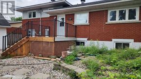 Ottawa apartment for rent - A red brick house with a black railing and a small garden in front.