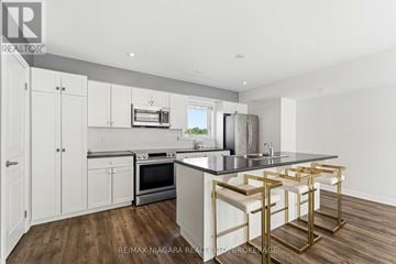 St. Catharines (Secord Woods) townhouse for rent - A kitchen with white cabinets and a black countertop.
