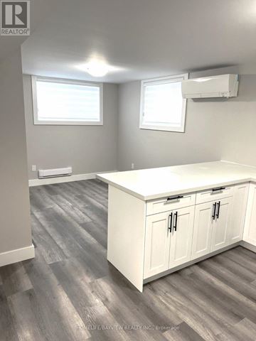 Barrie (Grove East) apartment for rent - A kitchen with white cabinets and a wooden floor.