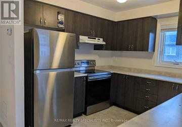 Brampton (Northwest Brampton) townhouse for rent - A kitchen with a stainless steel refrigerator and dark wood cabinets.