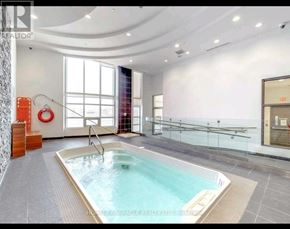 Toronto (Bayview Village) condo for rent - A swimming pool in a room with a glass wall.