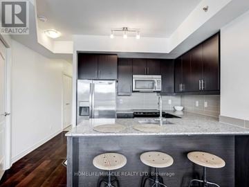 Toronto (Bayview Village) condo for rent - A modern kitchen with dark wood cabinets and a granite countertop.