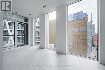 Toronto (Kensington-Chinatown) condo for rent - A spacious, empty room with a view of the cityscape outside the large windows.