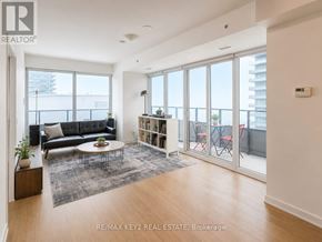 Toronto (Mimico) condo for rent - A living room with a black couch, a coffee table, and a large window.