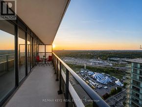 Toronto (Mimico) condo for rent - A balcony with chairs overlooks a cityscape at sunset.