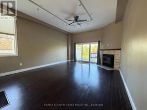 Ramara (Brechin) townhouse for rent - A spacious room with a fireplace and a ceiling fan.