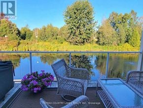 Ramara (Brechin) townhouse for rent - A patio with chairs and a table overlooking a lake.
