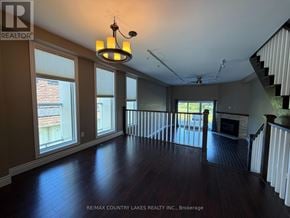 Ramara (Brechin) townhouse for rent - A large, empty room with wooden floors and a staircase on the right side.