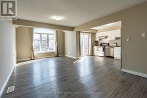 Waterloo townhouse for rent - A spacious living room with hardwood floors and a kitchen in the background.