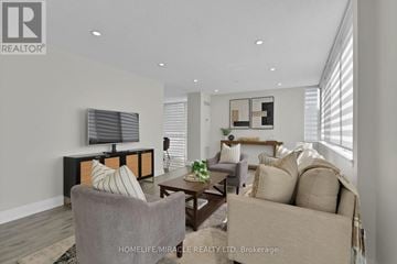 Mississauga (City Centre) condo for rent - A living room with a grey couch, a wooden table, and a television on the wall.