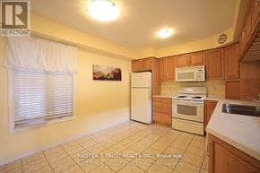 Guelph (Kortright East) townhouse for rent - A kitchen with a refrigerator, microwave, oven, and sink.