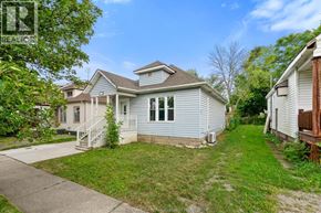 Windsor apartment for rent - A house with a blue roof and white trim is surrounded by green grass and trees.
