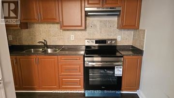 Toronto (Morningside) townhouse for rent - A kitchen with wooden cabinets and a black oven.