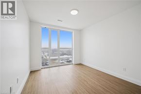 Waterloo condo for rent - A large empty room with a view of the city through the windows.