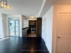 Toronto (Willowdale West) condo for rent - A spacious, empty room with a kitchen area in the background.