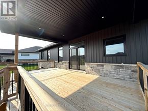 Huron-Kinloss apartment for rent - A wooden deck with a railing and a house in the background.