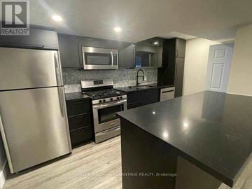 Toronto (Greenwood-Coxwell) apartment for rent - A kitchen with a refrigerator, oven, microwave, and sink.