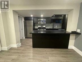 Toronto (Greenwood-Coxwell) apartment for rent - A modern kitchen with a black countertop and stainless steel appliances.