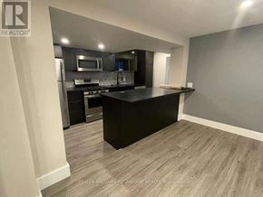 Toronto (Greenwood-Coxwell) apartment for rent - A modern kitchen with a black countertop and stainless steel appliances.
