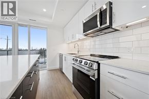 Waterloo condo for rent - A modern kitchen with white cabinets and a black stove top oven.