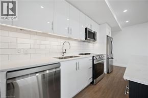 Waterloo condo for rent - A modern kitchen with white cabinets and stainless steel appliances.