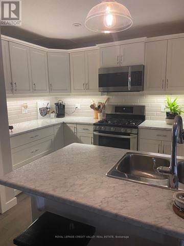 Tillsonburg townhouse for rent - A kitchen with a sink and a stove top oven.