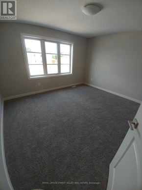 Tillsonburg townhouse for rent - A room with a carpeted floor and a window.