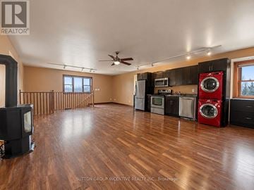 Bradford West Gwillimbury apartment for rent - A wood floor in a large empty room with a wood stove and a washer and dryer.