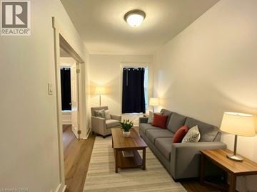 Hamilton apartment for rent - A well-lit living room with a grey couch and wooden coffee table.
