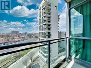 Toronto (Little Portugal) condo for rent - A balcony overlooks a city street with a tall white building in the background.